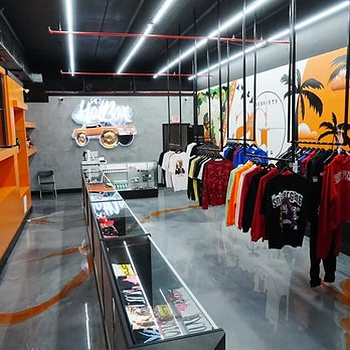 Inside the HotBox: orange shelving, glass counters, Sniper Gang tees and hoodies on the racks, palm-tree mural